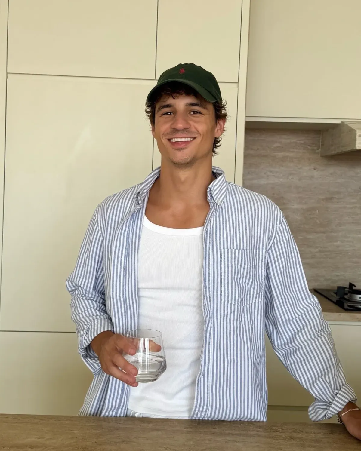 Ein junger Mann mit grüner Kappe und gestreiftem Hemd in einer Küche